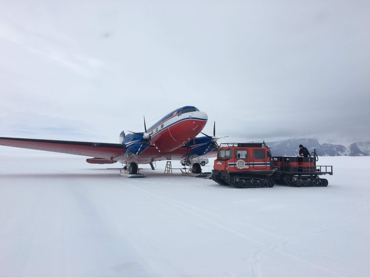 Drengen på snøen ved et fly i Antarktis.